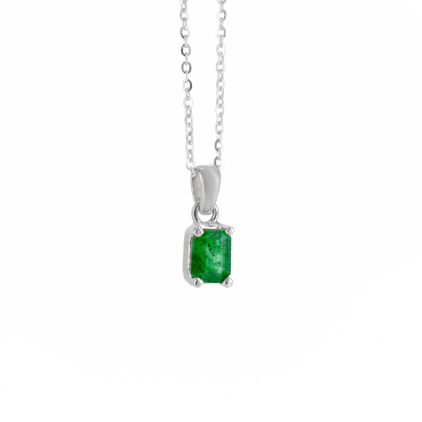Collar de oro blanco con un dije rectangular que engasta una esmeralda natural de color verde intenso, suspendido de una cadena de eslabones finos, sobre un fondo blanco.