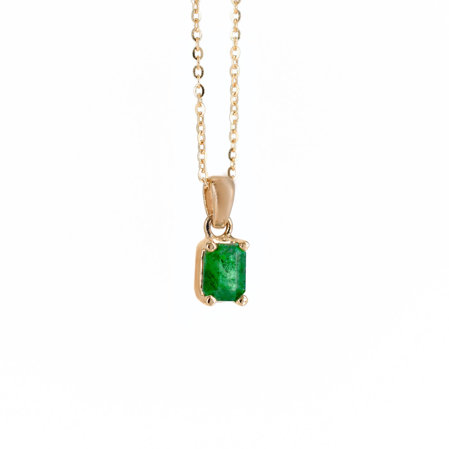 Collar de oro rosa con un dije rectangular que engasta una esmeralda natural de color verde intenso, suspendido de una cadena de eslabones finos, sobre un fondo blanco.