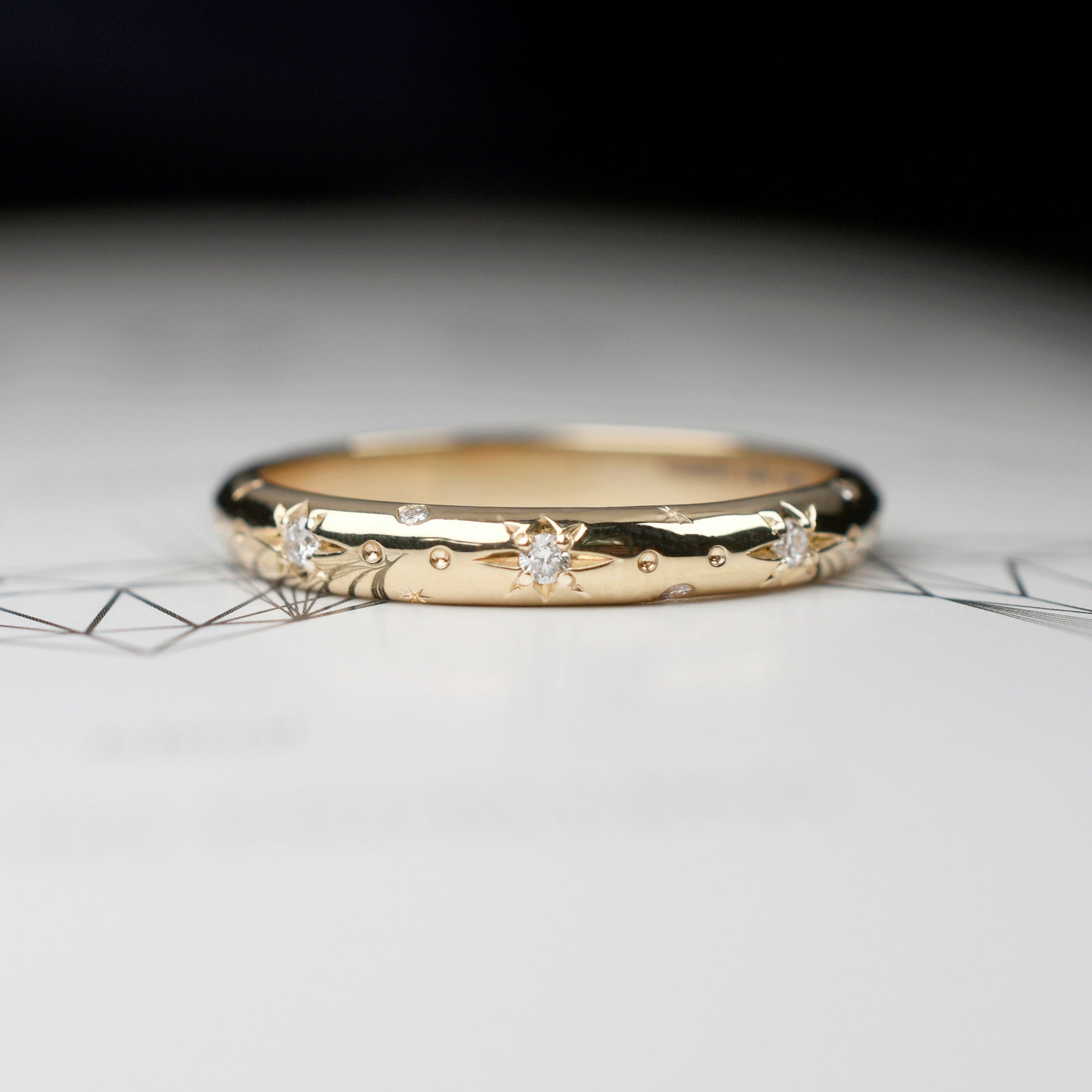 Alianza de matrimonio en oro amarillo pulido con estrellas grabadas y diamantes, argolla fina de estilo celestial para novia.