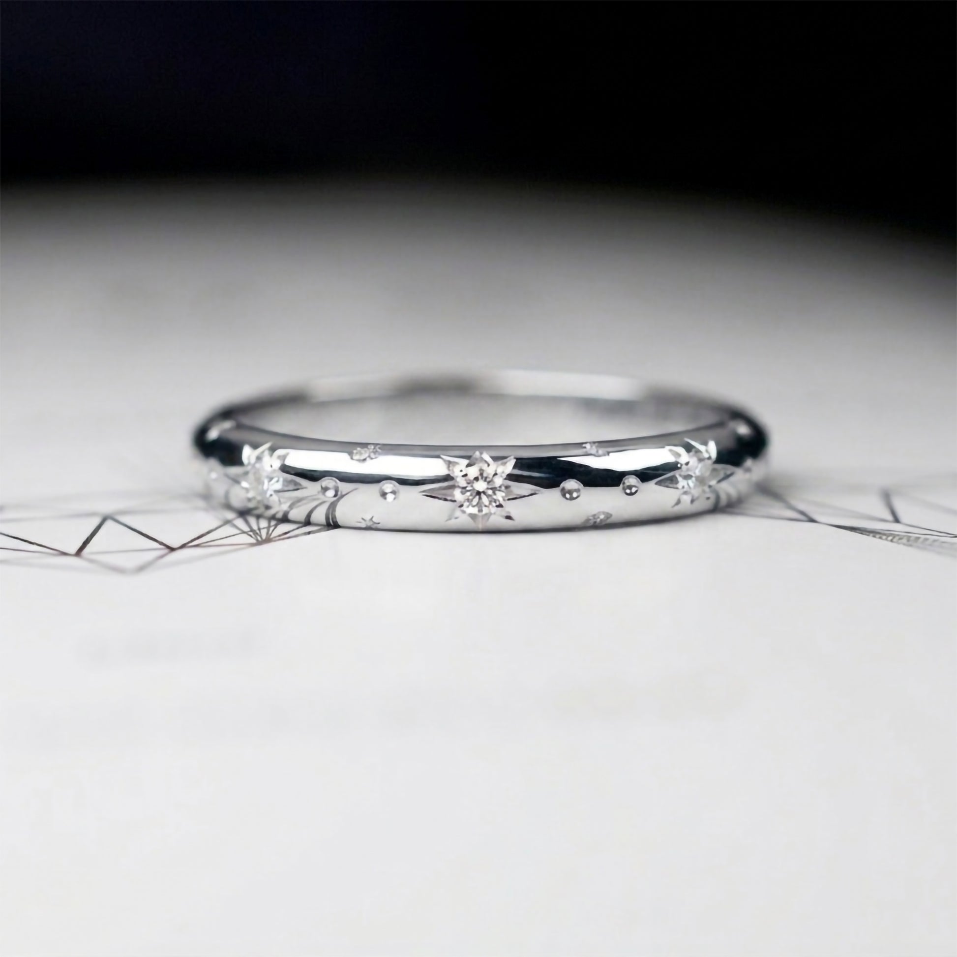 Alianza de matrimonio en oro blanco pulido con estrellas grabadas y diamantes, argolla fina de estilo celestial para novia.
