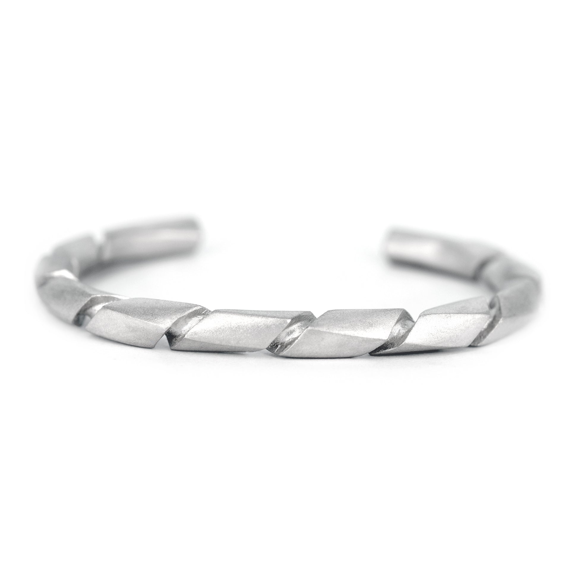 Pulsera de plata con acabado mate y un diseño torcido o en espiral, vista en primer plano.