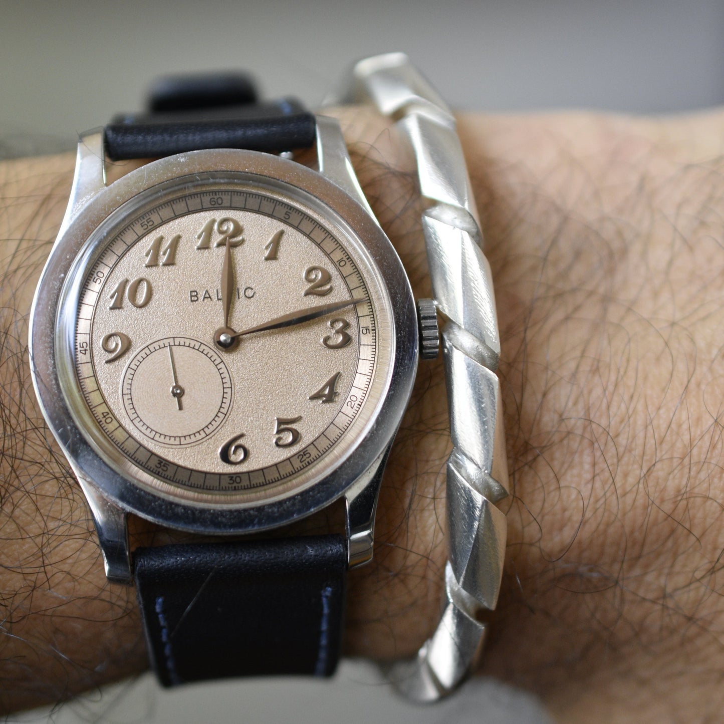 Pulsera acabado satín en uso, junto con un reloj.