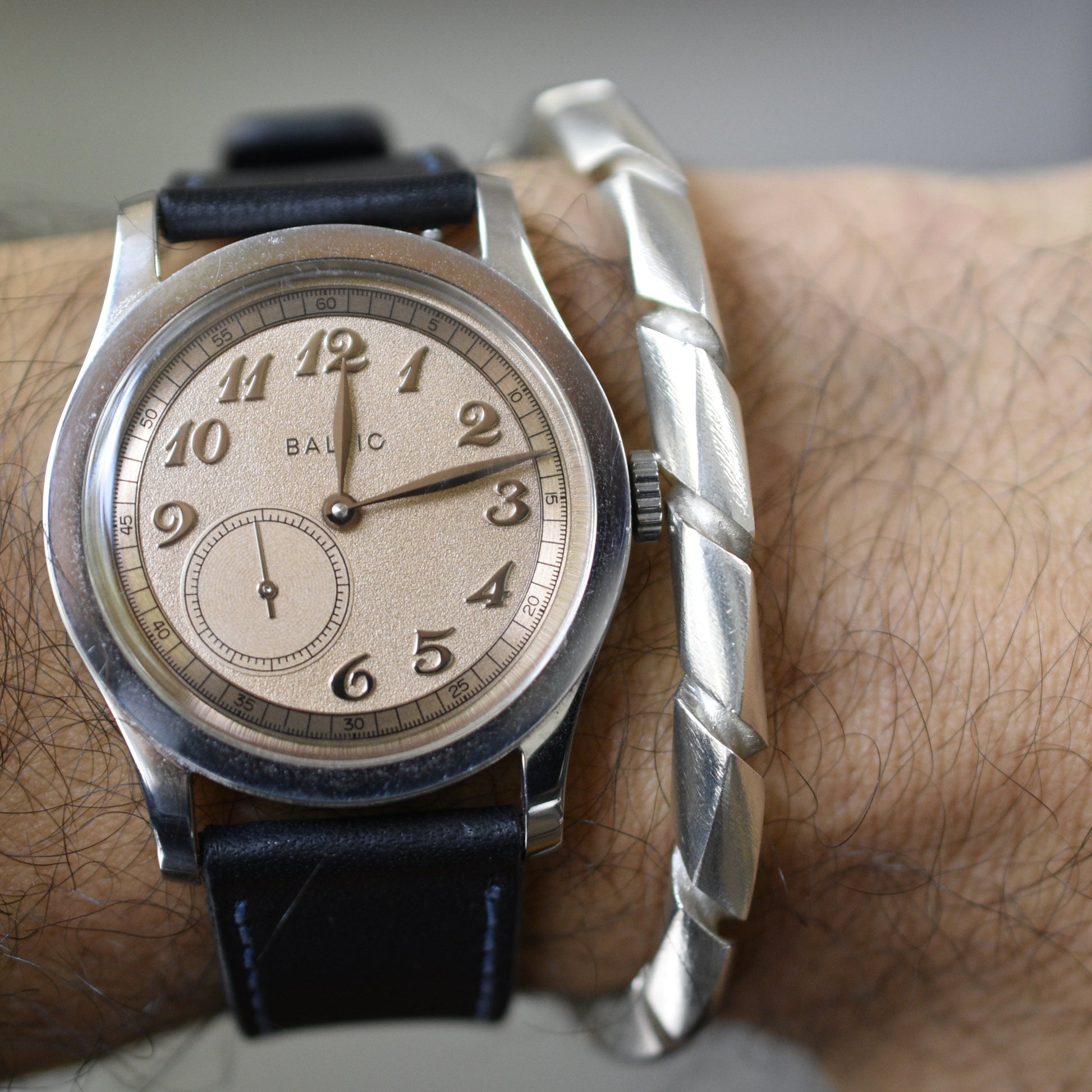 Pulsera acabado satín en uso, junto con un reloj.