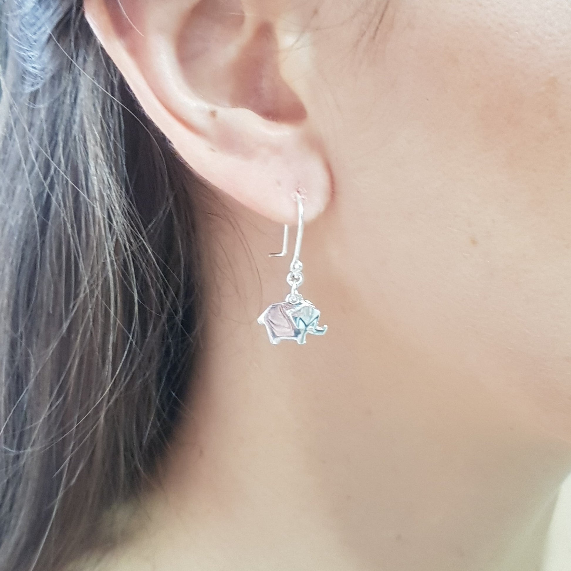 Arete elefante origami colgante de plata en uso.