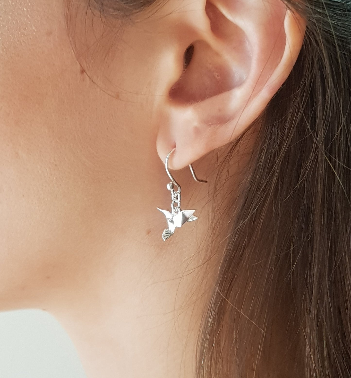 Aretes colibri de plata en una orega, ejemplo de uso.